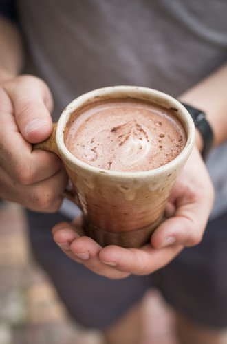 Person holding a ceramic mug filled with hot chocolate