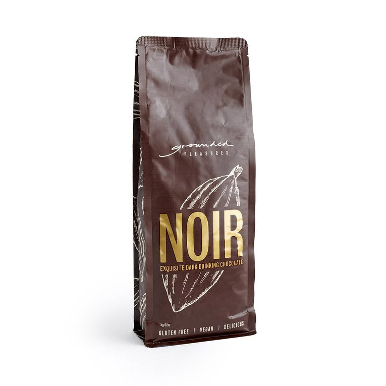 Brown packaging of 'Noir' dark drinking chocolate with 'grounded pleasures' branding on a white background.